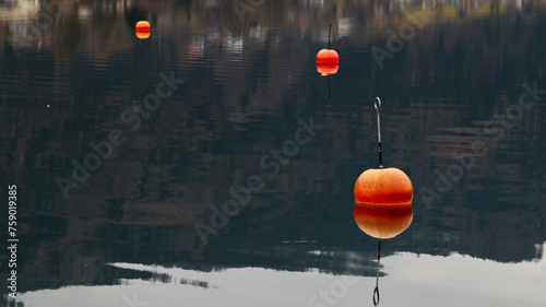 Czerwone, pomarańczowe, jaskrawe boje unoszą sie na tafli górskiego jeziora. © Tomasz
