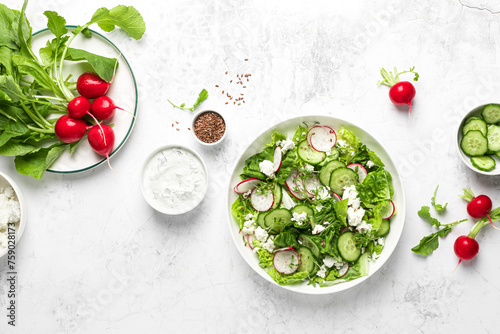 Radish and cucumber fresh green leafy vegetable salad with romaine lettuce, cottage cheese and yogurt, top view
