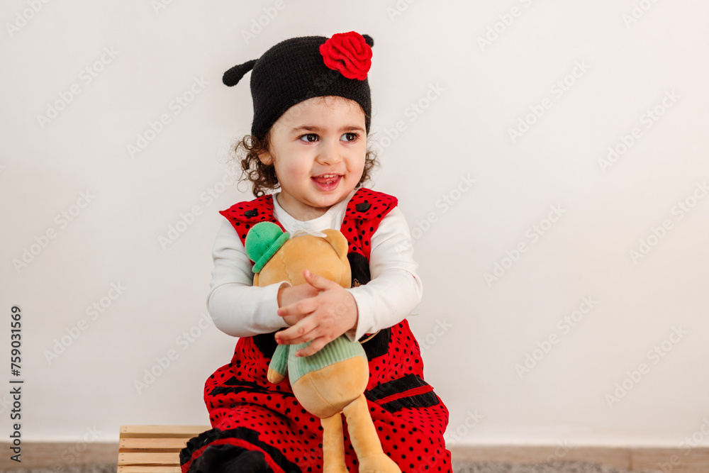 Easter playtime in red. A child s delightful interaction with a stuffed animal, celebrating Easter in a ladybug costume