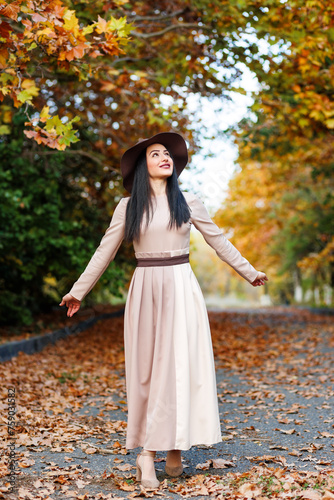 Obraz na płótnie Graceful lady walking. Woman in stylish dress walking among colorful autumn foliage w salonie