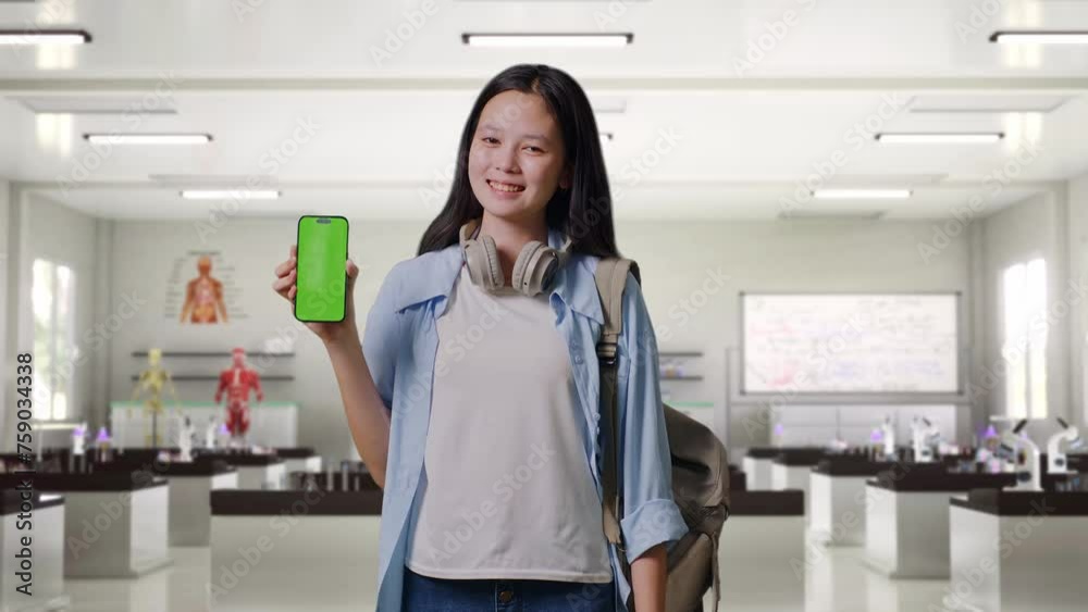 Asian Teen Girl Student With A Backpack Smiling And Showing Green Screen Smartphone To Camera While Standing In Science Laboratory Asian Teen Girl Student With A Backpack Smiling And Showing Green Screen Smartphone To Camera While Standing In Science Laboratory