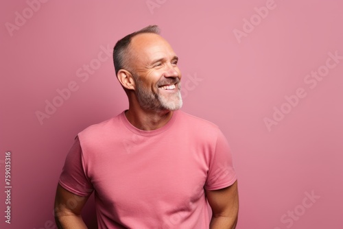 Portrait of a happy senior man in pink t-shirt over pink background. © Loli