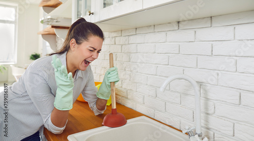 Photos Young upset screaming woman in gloves trying to unclog sink drain standing in the kitchen