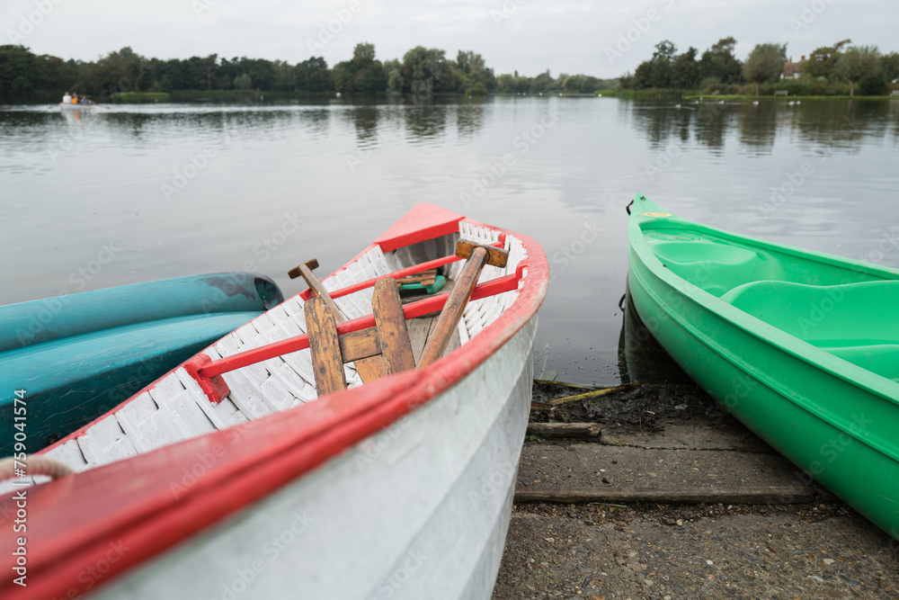 Pair of wooden, hand built canoes seen mored up on a large boating lake in England. The boats are available to the public for hire. Pair of wooden, hand built canoes seen mored up on a large boating lake in England. The boats are available to the public for hire.