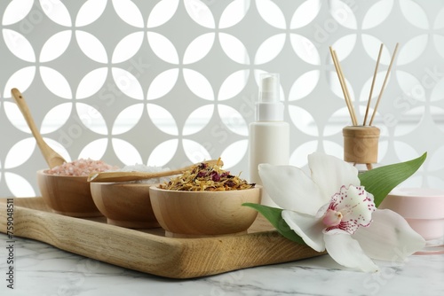 Beautiful composition with different spa products and orchid on white marble table