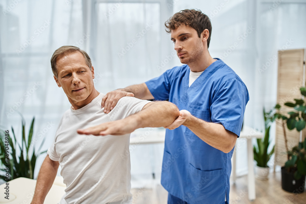 Obraz premium attractive mature patient in cozy attire on appointment with his rehabilitologist in hospital ward