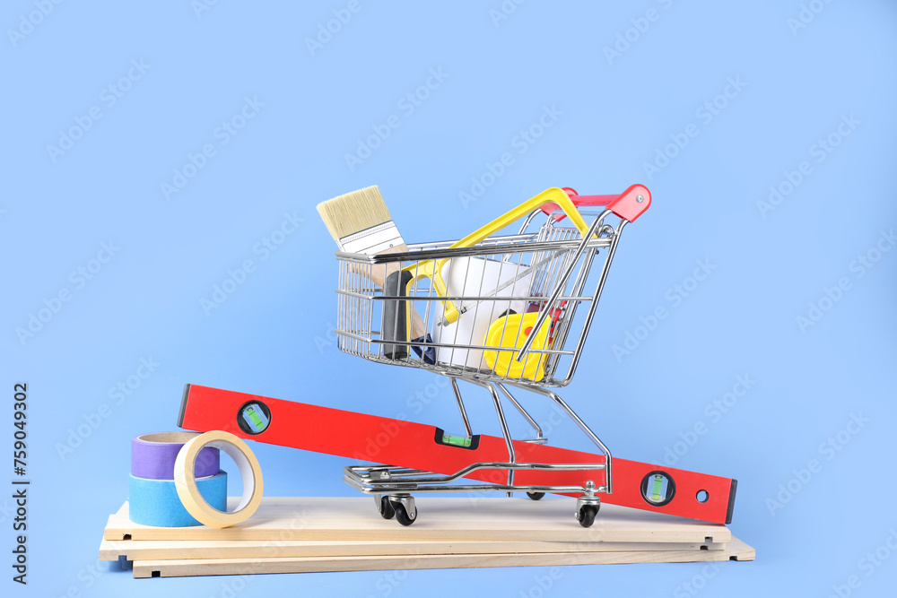 Small shopping cart with paint and renovation equipment on light blue background
