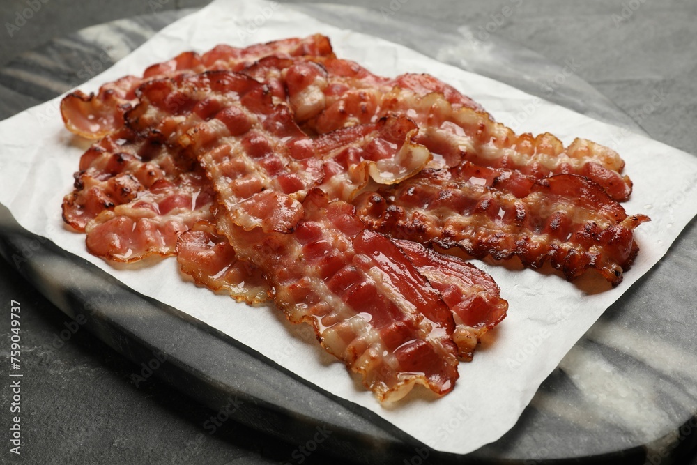 Fried bacon slices on dark table, closeup Fried bacon slices on dark table, closeup