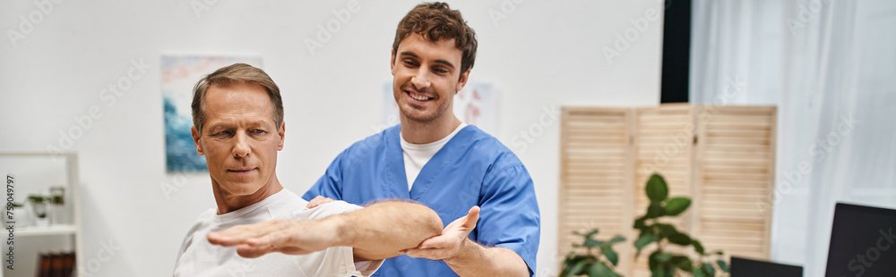 cheerful handsome doctor helping his mature patient to stretch during rehabilitation, banner cheerful handsome doctor helping his mature patient to stretch during rehabilitation, banner