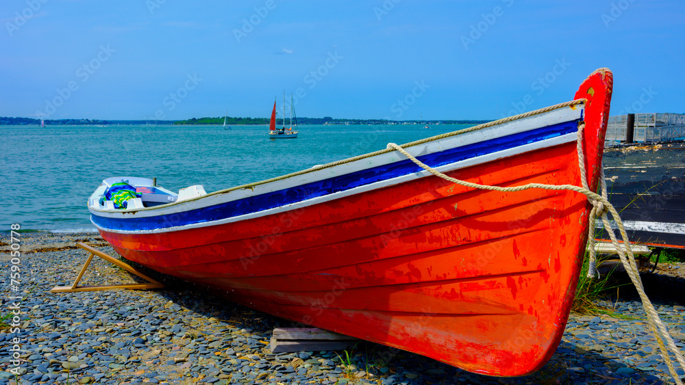 Red canoe moored on the rock beach in Boston, Massachusetts, a tranquil seascape in New England, USA