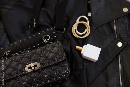 Bracelets, bottle of perfume, bag and black leather jacket , flat lay