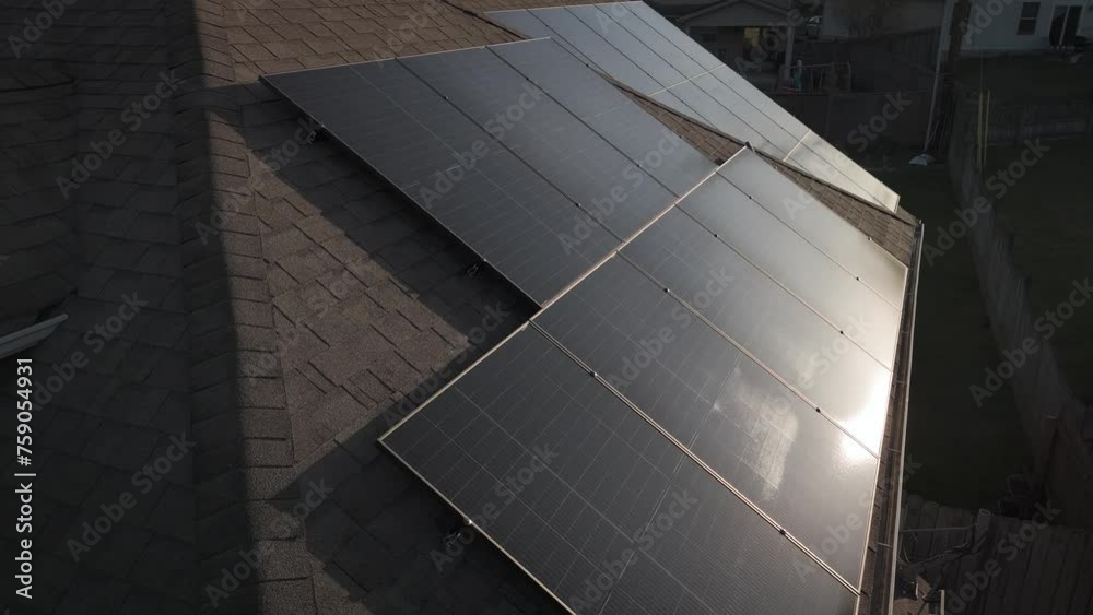 Morning sun reflection on solar panels installed as photovoltaic system on residential home roof