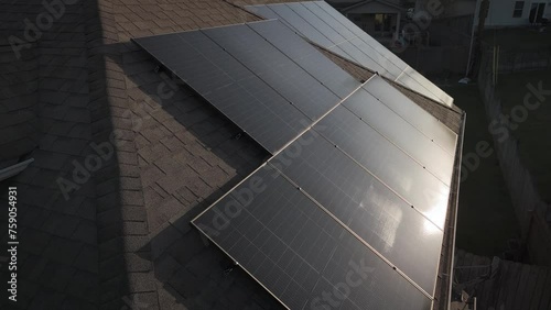 Morning sun reflection on solar panels installed as photovoltaic system on residential home roof photo
