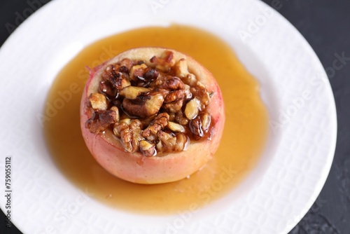 Fototapeta Naklejka Na Ścianę i Meble -  Tasty baked apple with nuts and honey on gray table, closeup