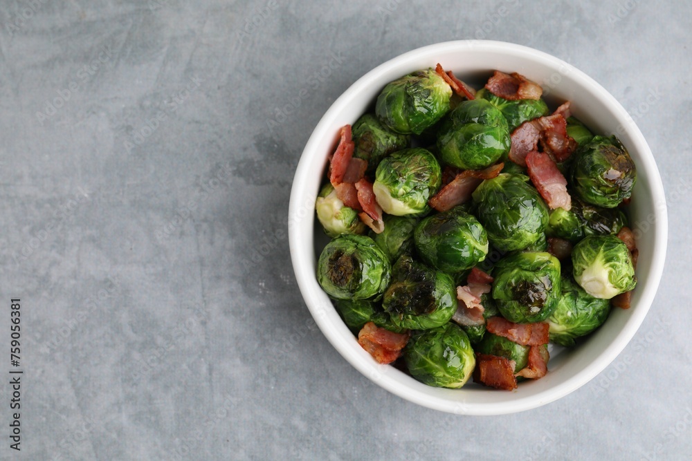Delicious roasted Brussels sprouts and bacon in bowl on grey table, top view. Space for text Delicious roasted Brussels sprouts and bacon in bowl on grey table, top view. Space for text