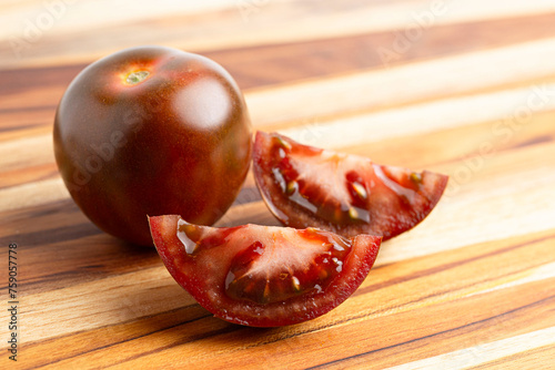 A Sweet Juciy Brown Kumato Tomato on a Wooden Cutting Board photo