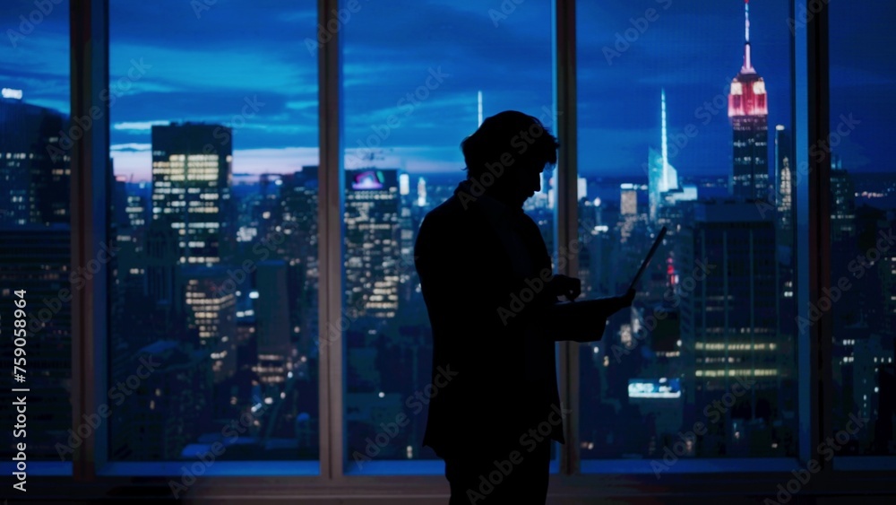 Successful business man in the office. Man ceo hedge fund top manager holding laptop typing working in front of window with evening city view. Successful business man in the office. Man ceo hedge fund top manager holding laptop typing working in front of window with evening city view.