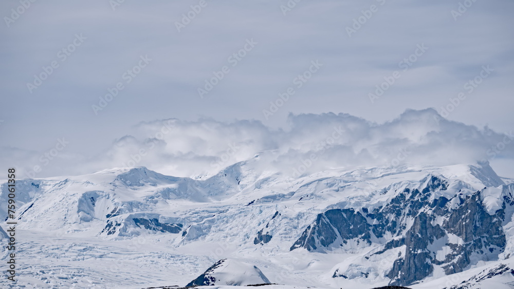 Arctic of ice mountain ranges at snow landscape. Nobody wild nature environment scenery of climate change. Cold winter at white snowy cloudy day with iceberg glacier mount at Antarctica