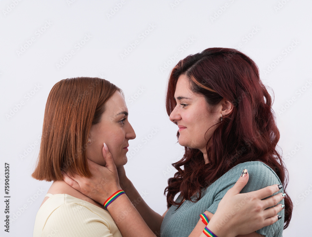 Young redheaded lesbian couple hugging and looking into each other's eyes in love, with rainbow bracelets and nice manicures. Concept of LGTBI pride and rights Young redheaded lesbian couple hugging and looking into each other's eyes in love, with rainbow bracelets and nice manicures. Concept of LGTBI pride and rights