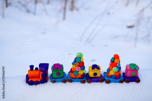 A toy train with gifts and Christmas trees on a background of snow. Winter background. New Year decorations.