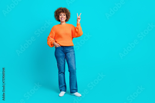 Full length photo of positive lovely woman standing empty space showing v-sign isolated on blue color background