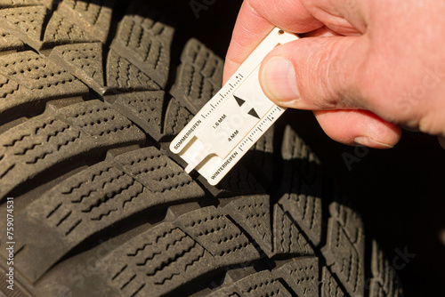 close-up of measuring tread depth of car tire photo