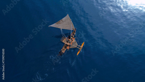 Aerial shot of a traditional Micronesian outrigger sailing canoe surrounded by blue water photo
