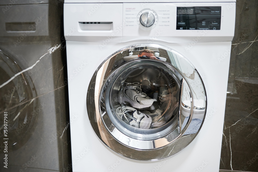 Close up photo of sneakers in washing machine. Washing shoes after walk in rainy day. Close up photo of sneakers in washing machine. Washing shoes after walk in rainy day.