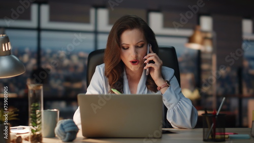 Woman having business call writing notes at office. Smiling lady boss talking photo