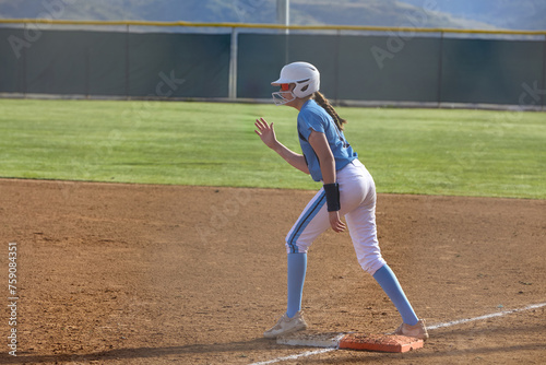 Young female Softball player playing youth sports. Swinging bat. photo