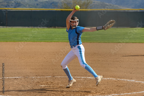 Young female Softball player playing youth sports. Pitcher photo