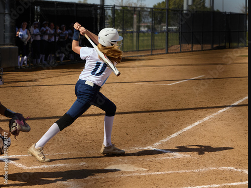 Young female Softball player playing youth sports. Swinging bat. photo