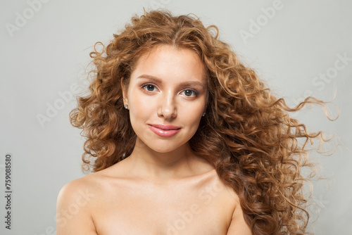 Attractive young woman with natural make-up, clear fresh skin and wavy hairstyle on white background