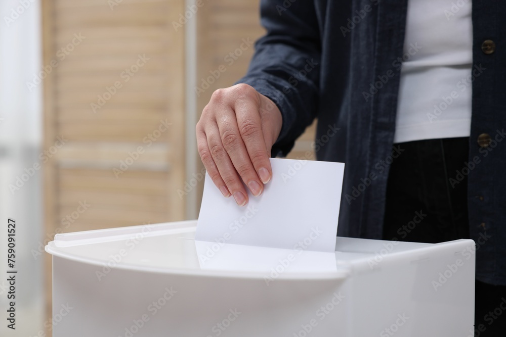 Woman putting her vote into ballot box on blurred background, closeup Woman putting her vote into ballot box on blurred background, closeup
