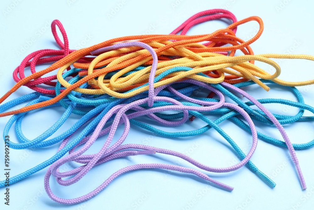 Many colorful shoe laces on light blue background, closeup Many colorful shoe laces on light blue background, closeup