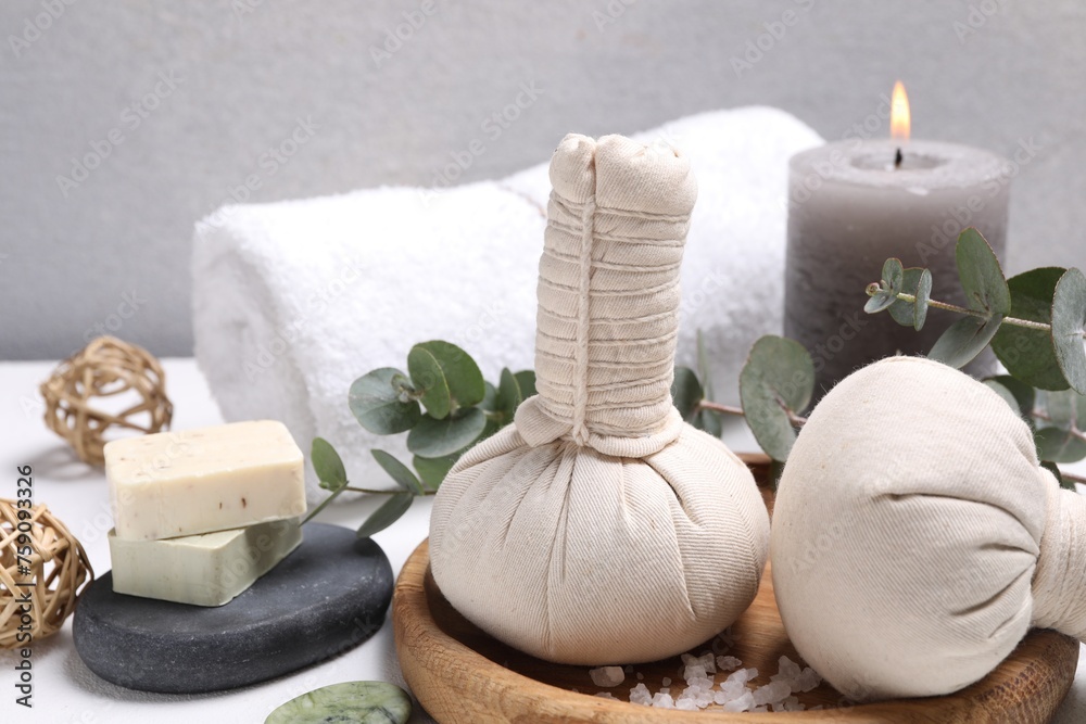 Spa composition with herbal massage bags and eucalyptus branches on white table Spa composition with herbal massage bags and eucalyptus branches on white table