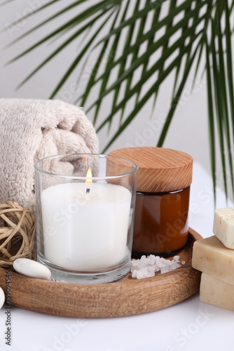 Composition with spa supplies on white table and palm leaf