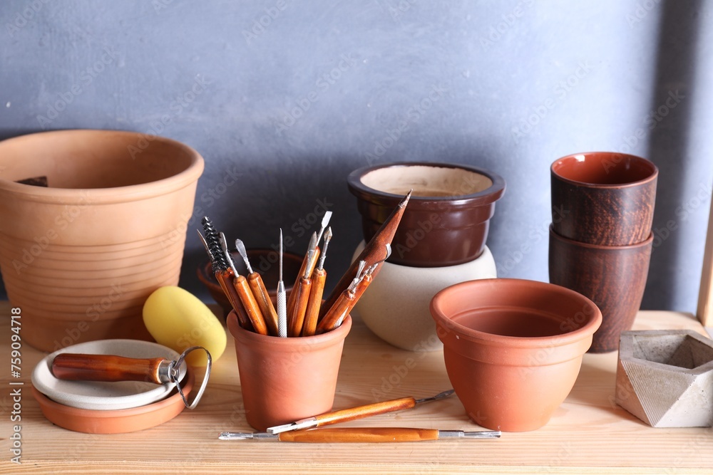 Set of different crafting tools and clay dishes on wooden rack in workshop, closeup Set of different crafting tools and clay dishes on wooden rack in workshop, closeup