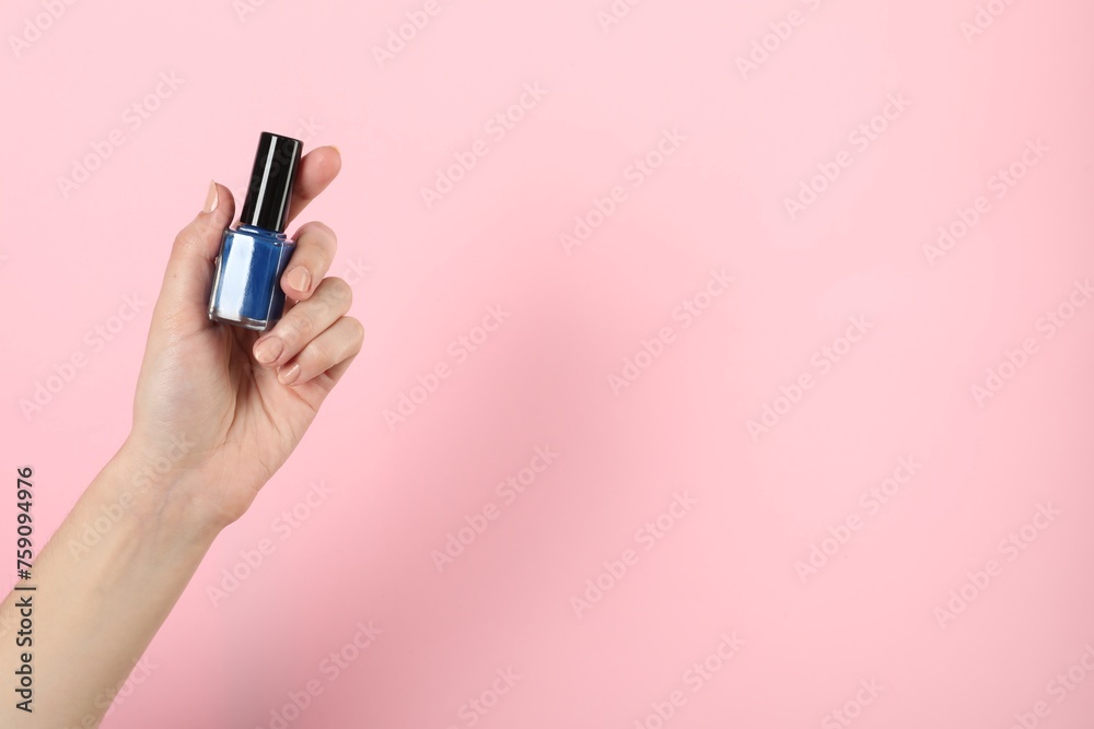 Woman holding nail polish on pink background, closeup. Space for text Woman holding nail polish on pink background, closeup. Space for text