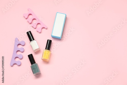 Nail polishes, toe separators and buffer on pink background, flat lay. Space for text