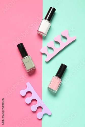 Nail polishes and toe separators on color background, flat lay