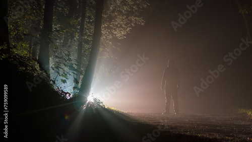 A man looking at a mysterious light in a forest photo