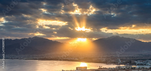 Panoramic morning view with sunbeams, Eilat (Israel) and Aqaba (Jordan) cities, and Aqaba gulf all seen from surrounding hills in Eilat 

