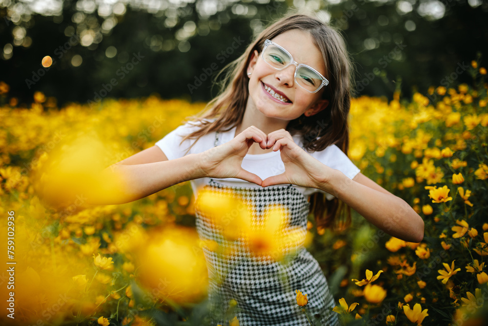 © Maria Manco/Stocksy - Preteen smiles at camera in wildflower field