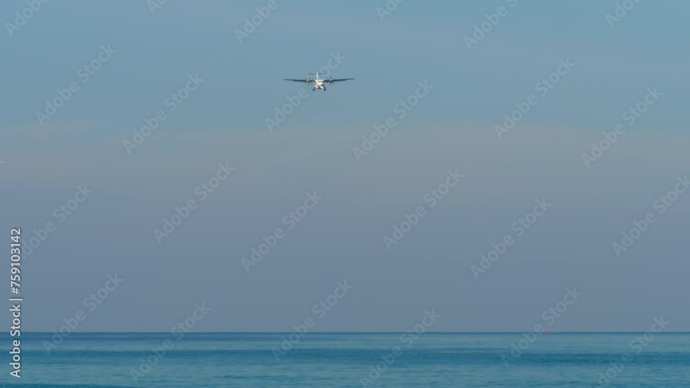 Airplane approaching to land. Airliner flying over the blue sea, descending. Turboprop carrier in the sky Airplane approaching to land. Airliner flying over the blue sea, descending. Turboprop carrier in the sky