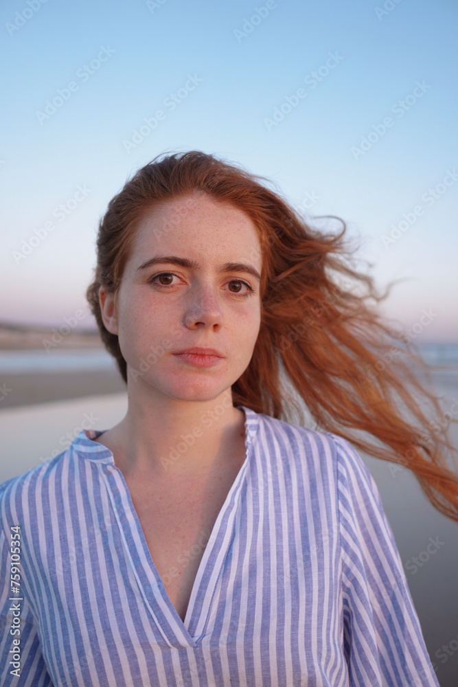 Portrait of redheaded woman in a blue dress on the seaside at sunset Portrait of redheaded woman in a blue dress on the seaside at sunset