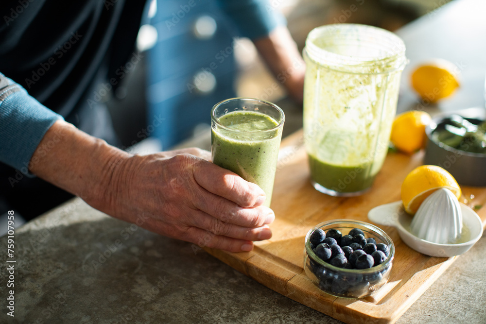 Senior man preparing healthy smoothie with blueberries and greens at home Senior man preparing healthy smoothie with blueberries and greens at home