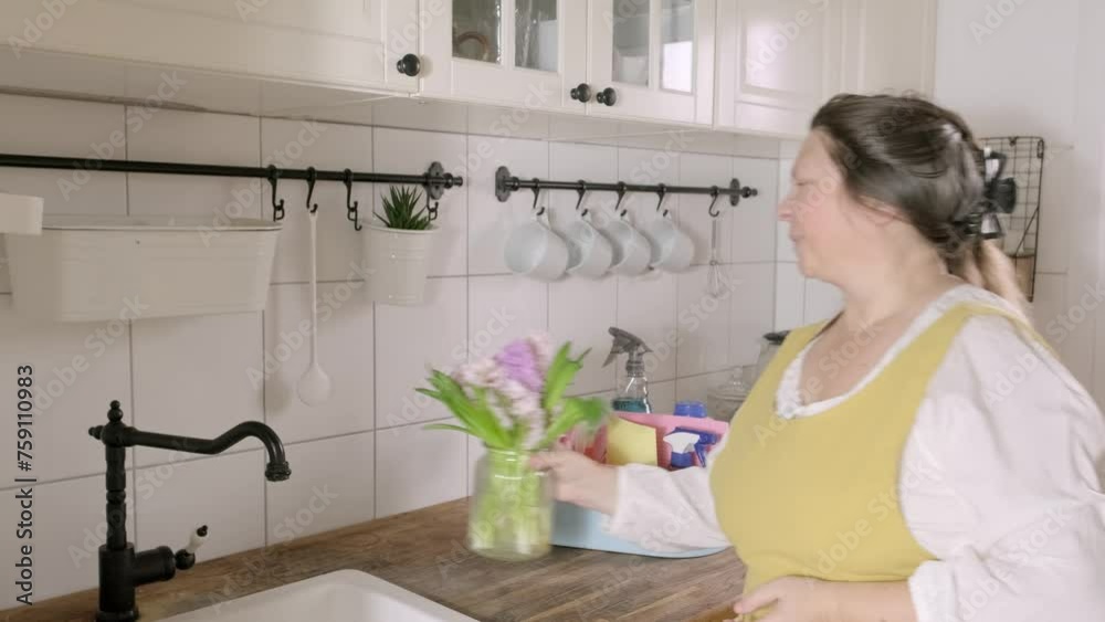 mature woman in yellow apron enjoying spring time, fragrant hyacinths, diligently cleans spotless white kitchen, conveying joy of maintaining clean and organized home environment mature woman in yellow apron enjoying spring time, fragrant hyacinths, diligently cleans spotless white kitchen, conveying joy of maintaining clean and organized home environment