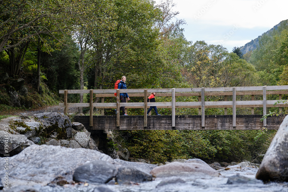 Woman with child walking on footbridge during hiking