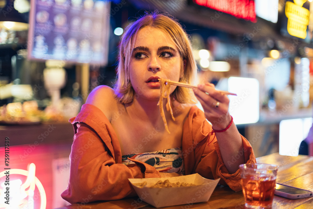 Young woman eating alone at a street food market Young woman eating alone at a street food market